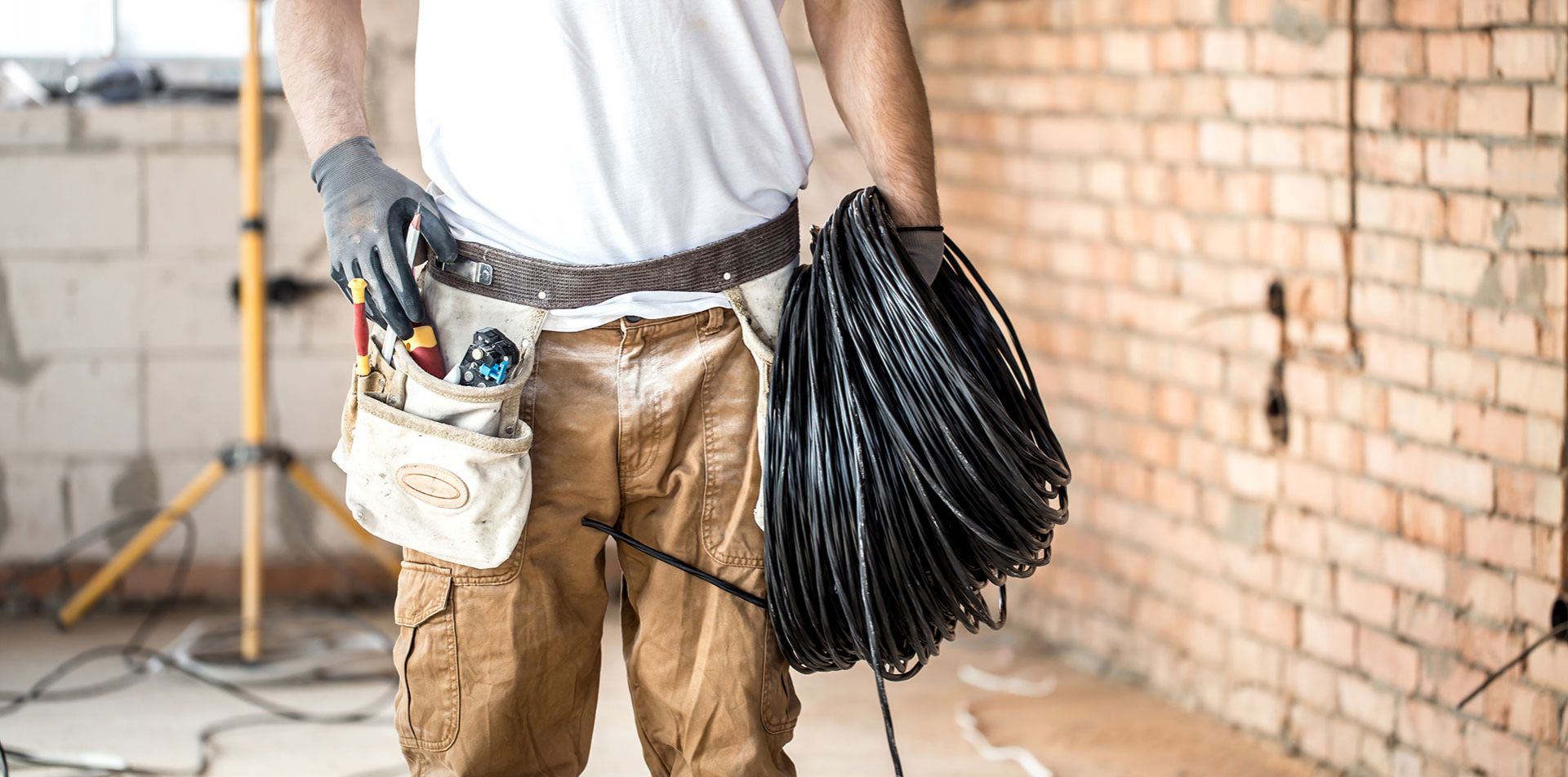 Symbolbild zeigt einen Handwerker mit Gürteltasche und Kabeln.